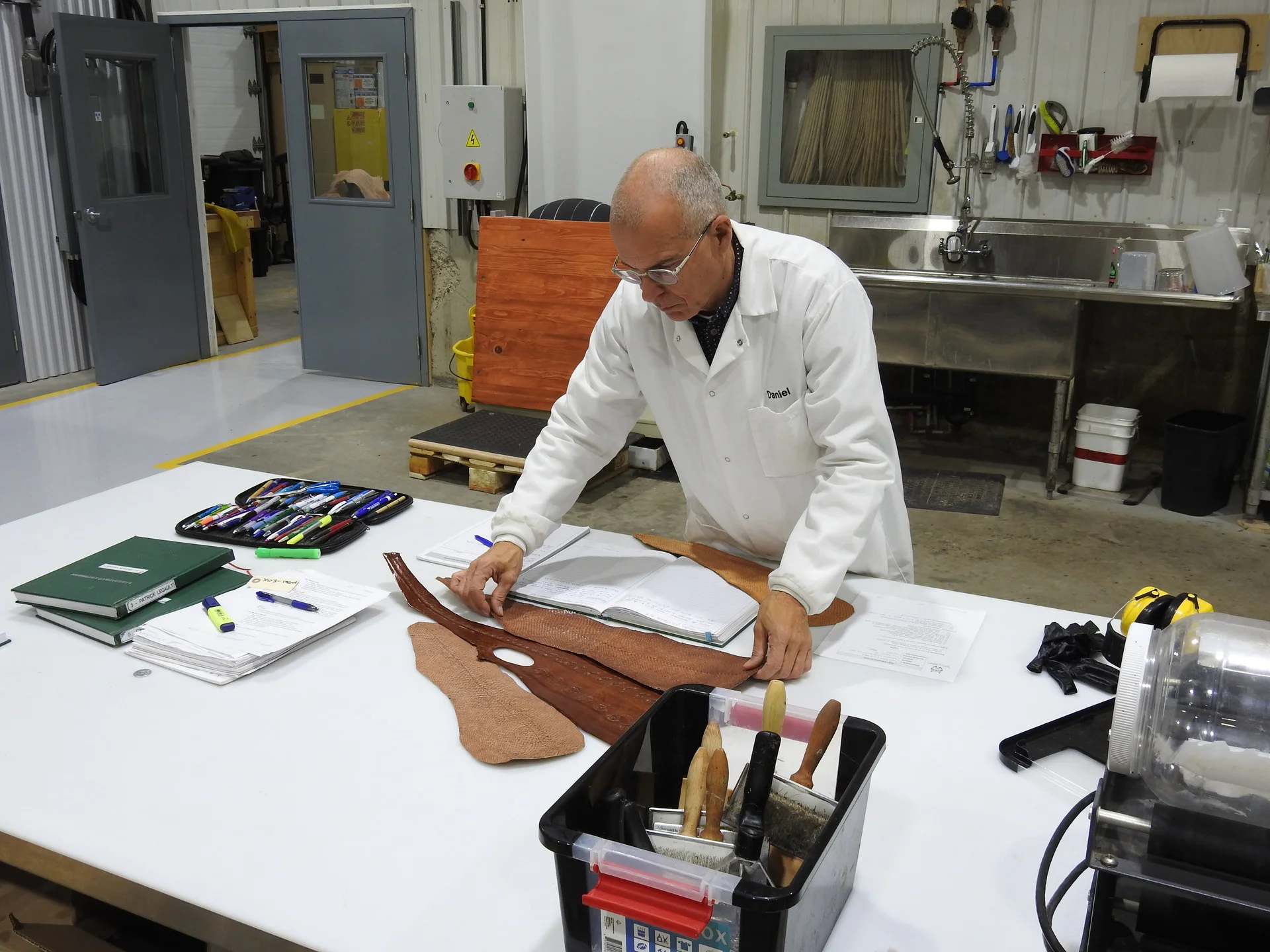 Employé portant un sarrau et manipulant du cuir de saumon sur une table de travail
